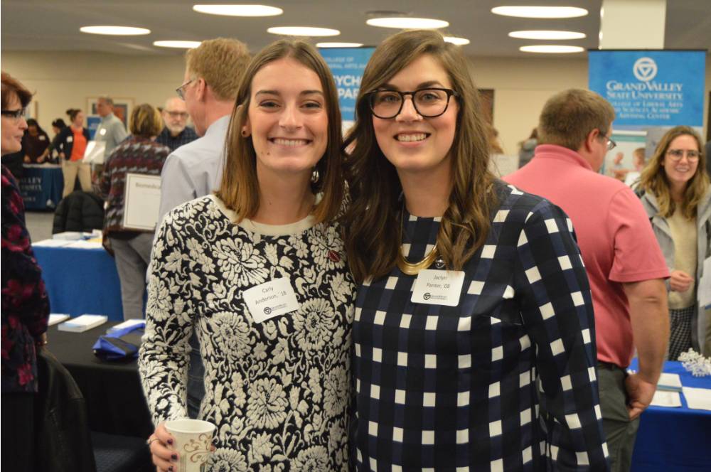 Two alumnae pose for a photo with one another at the Academic Major Fair.